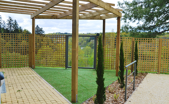 Vue du jardin à travers les palissades et les baies vitrées, un lieu sécurisé ouvert sur la nature environnante