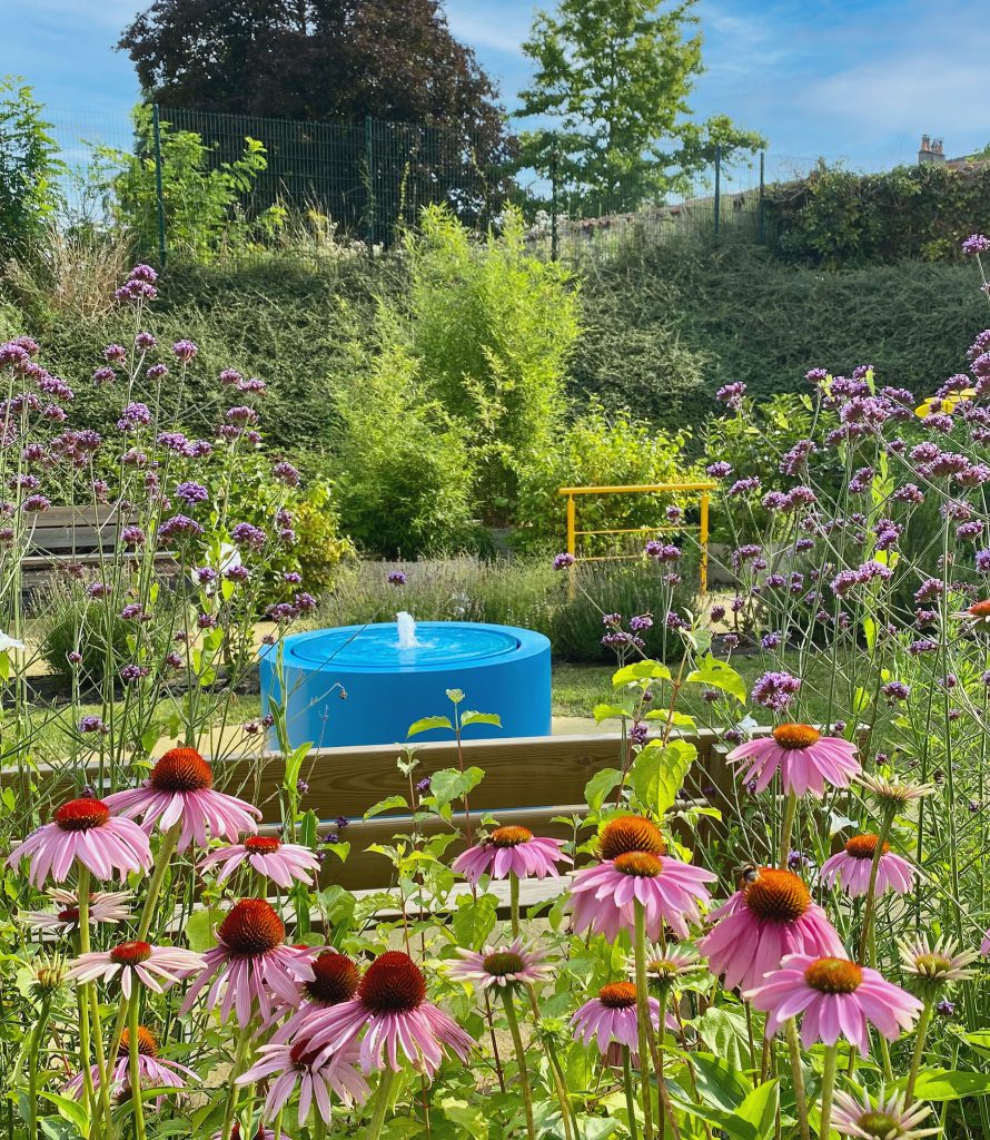 Une fontaine à débordement colorée au milieu des fleurs