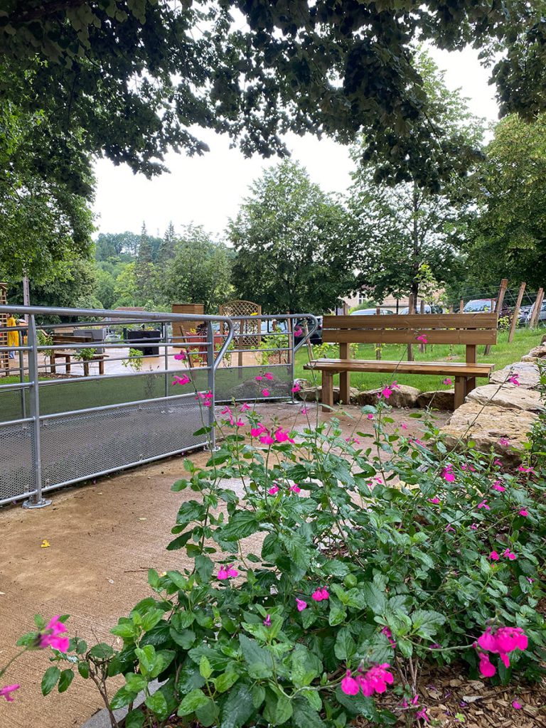 Un espace ombragé et sécurisé dans le jardin. Un banc proche d'une main courante.