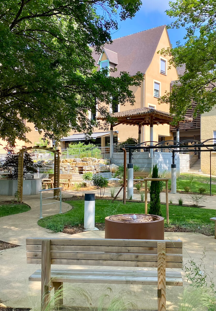 un jardin ombragé avec un banc à côté d'une fontaine