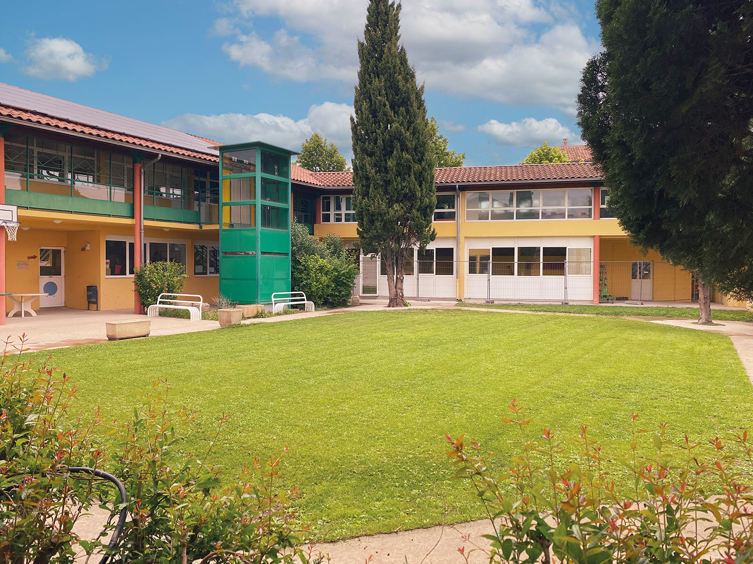 jardin-les-platanes-avant-travaux vue d'ensemble du jardin de l'école les platanes aant les travaux. Une grande zone de gazon est entouré d'arbres est d'un chemin piétonnier