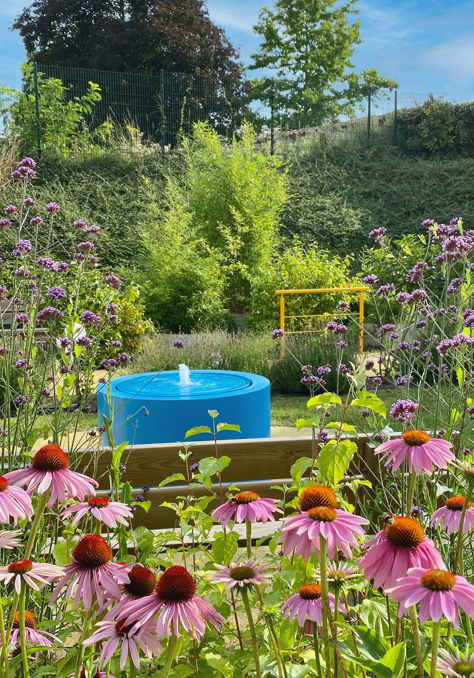 Une fontaine à débordement colorée au milieu des fleurs